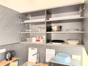 a kitchen with a shelf with dishes on it at Duplex Fleckenstein - Centre Historique de Haguenau in Haguenau +22 photos