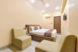 a bedroom with a bed and a chair in a room at FabHotel Pearl Square in Jaipur