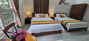 a bedroom with two beds and a table with flowers at Chi's House in Thôn Trường Giang