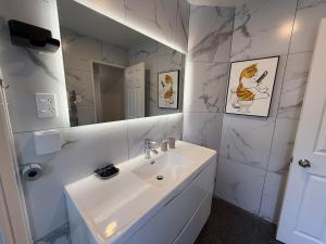 a white bathroom with a sink and a mirror at Sky Stars Serene Haven Villa at Mt Eden in Auckland +42 photos