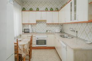 a kitchen with white cabinets and a sink and a table at La Casa de Arroyo in Arroyo de Cuéllar