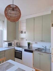 a kitchen with white cabinets and a pendant light at Tilava kolmio keskustassa in Ylivieska