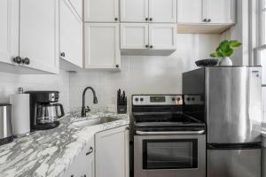 Una cocina blanca con estufa y fregadero. en Jazz Haven Spacious 3BR Condo, en Nueva Orleans