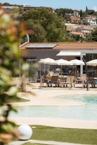 a pool with chairs and umbrellas next to a building at ReBi Village in Imperia