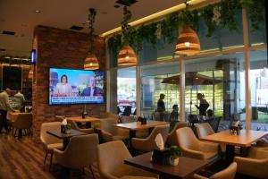 a restaurant with tables and chairs and a flat screen tv at Treppan Hotel & Suites By Fakhruddin in Dubai