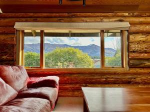 ein Wohnzimmer mit einer Couch und einem Fenster in der Unterkunft Large Ski Club Style Lodge, Views, Walk to town in Wanaka