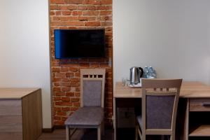 a room with a table and chairs and a tv on a brick wall at Apart Podolski in Sandomierz
