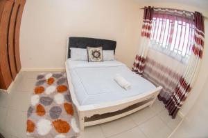un lit blanc dans une chambre avec une fenêtre dans l'établissement Kay Homes, à Eldoret