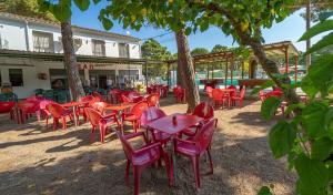 a group of red chairs and tables under trees at Camping Alannia Neptuno in Pals