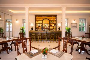 a restaurant with a bar with wooden tables and chairs at Villa Santi Hotel in Luang Prabang