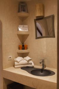 a bathroom with a sink and a mirror and towels at DAV MAHAL Eco lodge in Sidi Kaouki
