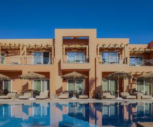 a building with a swimming pool with chairs and umbrellas at High Beach Resort in Malia