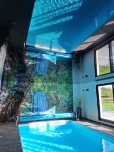 a swimming pool with a waterfall mural on the wall at Emille et une nuits in Mérignies