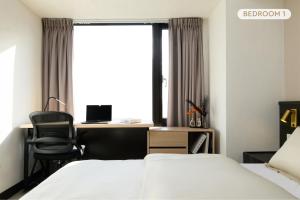 台北市にあるTaipei Main Station Modern Comfort Apartments - 台北車站現代舒適電梯大樓のベッド2台と机と窓のある寝室