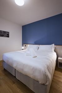 - une chambre avec un grand lit blanc et un mur bleu dans l'établissement La Corte Rental Room, à Teramo