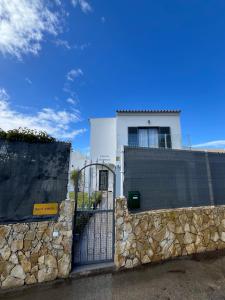 una casa bianca con un cancello e un muro di pietra di Villa Oasis 4-Bedroom Retreat with Pool in Vilamoura a Quarteira
