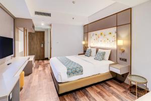 Una habitación de hotel con una cama grande y un escritorio. en Sunday Hotel Arshika Sunset Road, en Kuta 291 fotos más