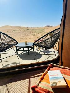 a room with two chairs and a table in the desert at Nomademoi Luxury Camp in El Gouera +3 photos