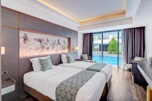 Una habitación de hotel con dos camas y una gran ventana. en Sunday Hotel Arshika Sunset Road, en Kuta