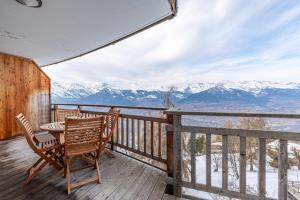 a table and chairs on a deck with snow covered mountains at Ski Paradise SP 008 - MOUNTAIN & LUXE apartment 4 pers in Veysonnaz