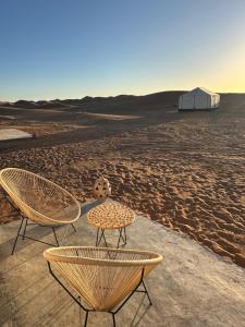 two chairs and a table in the desert at Nomademoi Luxury Camp in El Gouera