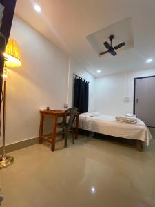 1 dormitorio con cama, mesa y ventilador de techo en Nagaon Homestay, en Nowgong