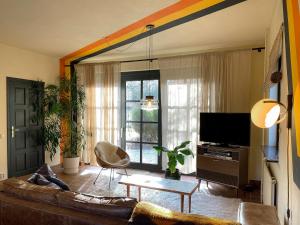 a living room with a couch and a tv at Stay Classy - Cottage in Otterlo