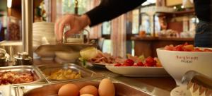 a person preparing food in a kitchen with eggs on a counter at BurgStadt-Hotel in Kastellaun