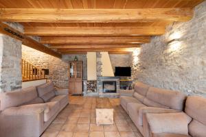 a living room with couches and a stone wall at Agroturisme La Serra in Vilada