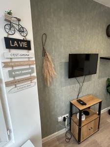 Una sala de estar con un televisor y una mesa. en Le boème - Close to Paris - WIFI, en Champigny-sur-Marne