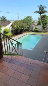 a swimming pool with a chair next to a fence at cozy home in traquil area in Empangeni