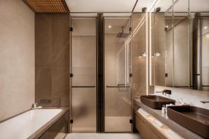 a bathroom with two sinks and a tub and a shower at Amathus Beach Hotel Limassol in Limassol