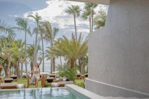 a woman standing next to a swimming pool at a resort at Amathus Beach Hotel Limassol in Limassol