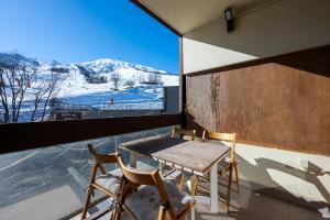 einen Tisch und Stühle auf einem Balkon mit Bergblick in der Unterkunft Le cosmos in Villarembert