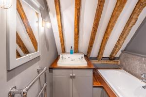 a bathroom with a sink and a bath tub at Belchamp Hall Hayloft in Belchamp Otten