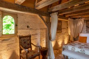 een slaapkamer met een bed, een stoel en een raam bij Hôtel du Château du Rivau in Lémeré