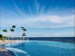a swimming pool next to the ocean with palm trees at Flat de Luxo no Tropical - Vista Para Rio in Manaus