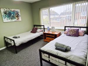 ein Zimmer mit zwei Betten und einem Tisch und einem Fenster in der Unterkunft Rabbit Haven- Near Bicester Village & Town - ShireStays in Bicester