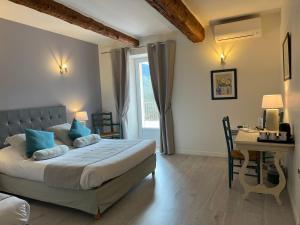 a bedroom with a bed and a table and a desk at Logis Hôtel La Bastide des Monges in Nyons