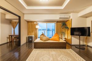 a room with a bed with orange pillows and a television at Cozy Stay Sapporo Hongodori 1005 in Sapporo