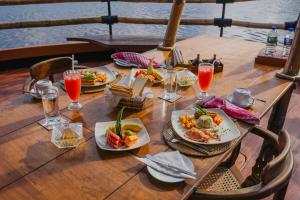 a wooden table with plates of food and drinks at Yathra Houseboat in Bentota
