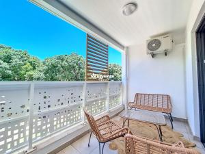 Un balcón con dos sillas y una mesa y una ventana. en Ecrin Salé - T2 rénové de 64 m2 - Etang-Salé, en Étang-Salé