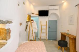 a room with a bed and a tv and a table at Idothea guest house in Amorgos