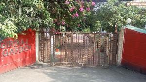 a red gate with a red fence with pink flowers at Giriraj Garden Resort in Vāgholi