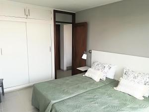 una camera da letto con un grande letto con lenzuola e cuscini verdi di KC home abroad a Playa de las Americas Altre 28 foto