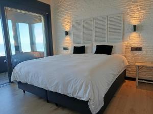 a bedroom with a large white bed with a brick wall at El vigía de cadiz in Cádiz