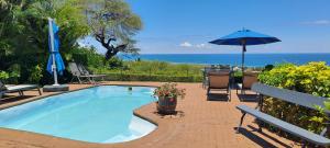una piscina con tavolo e ombrellone di Flamboyant Ocean View - ex Hillside Haven a Tamarin