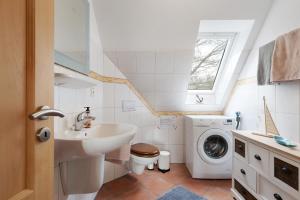 un bagno con lavandino e lavatrice di Ferienwohnung Auszeit a Nordstrand Altre 19 foto