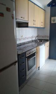 una cocina con refrigerador y estufa horno superior en Ático en pleno centro de Baiona con garaje, en Baiona
