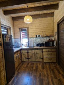 a kitchen with wooden cabinets and a black refrigerator at Domek Pod Siodłem in Wetlina